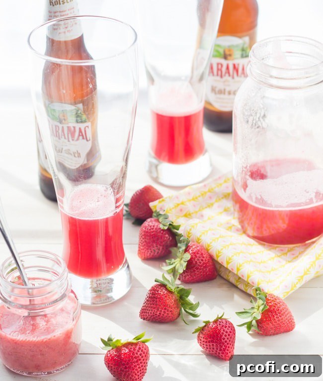 A refreshing Strawberry Rhubarb Shandy being poured into a tall pilsner glass, showcasing its vibrant color and frothy head.