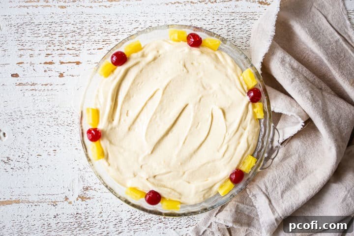 Unbaked pineapple upside-down cake in a glass baking dish, sitting on a linen cloth.