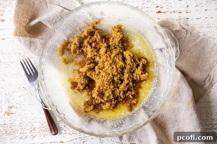 Melted butter and light brown sugar layered in a cake pan, ready for mixing.