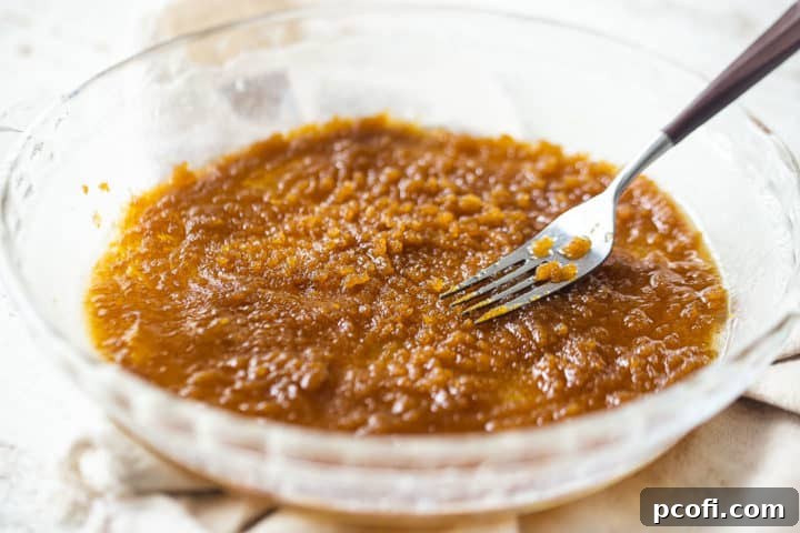 Mixing brown sugar and melted butter together with a fork in a cake pan.