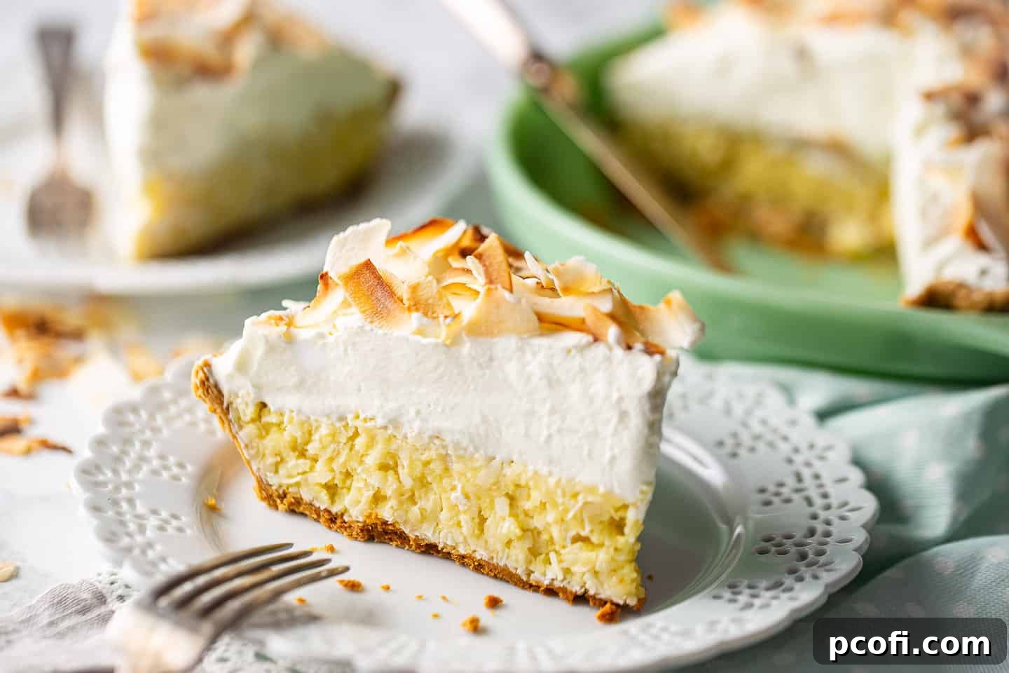 Easy coconut cream pie, assembled, sliced, and served on a marble background.