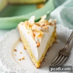 A slice of coconut cream pie on a lacy porcelain plate.