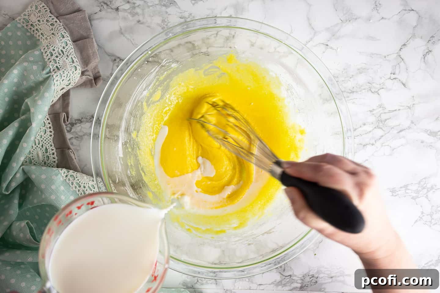 Tempering egg yolks with hot milk.