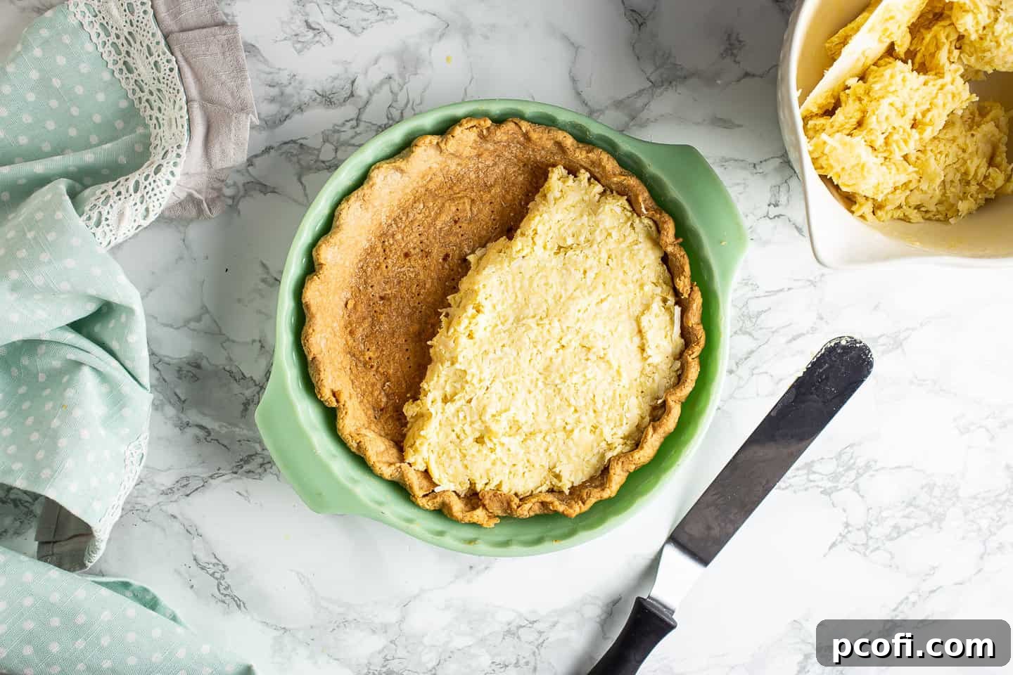 Spreading coconut custard into a pre-baked pie crust.