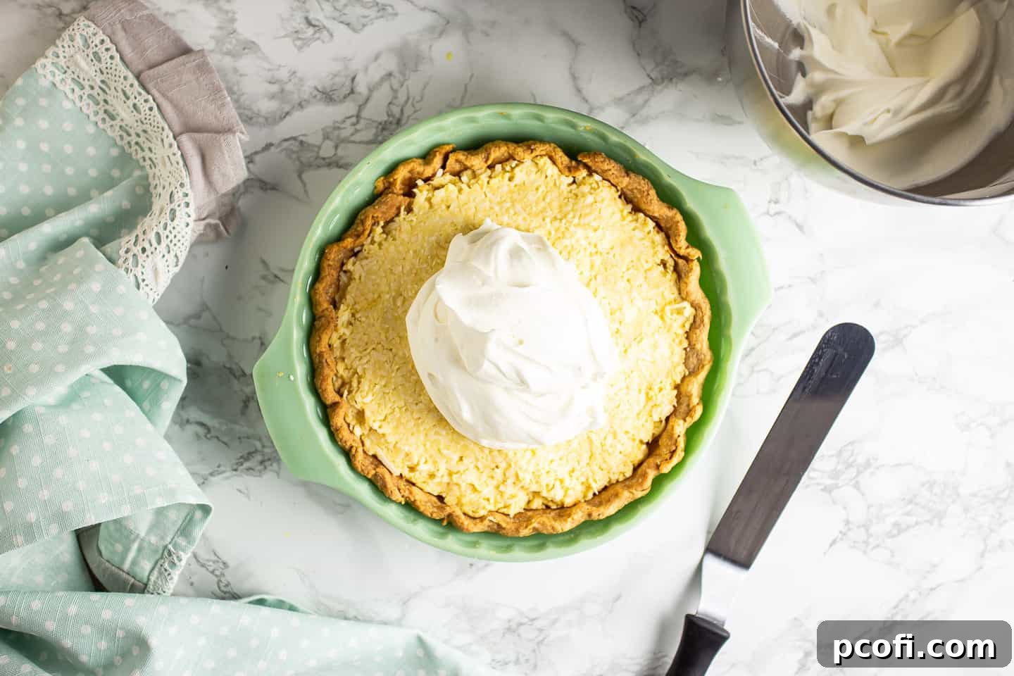 Topping coconut cream pie with freshly whipped cream.