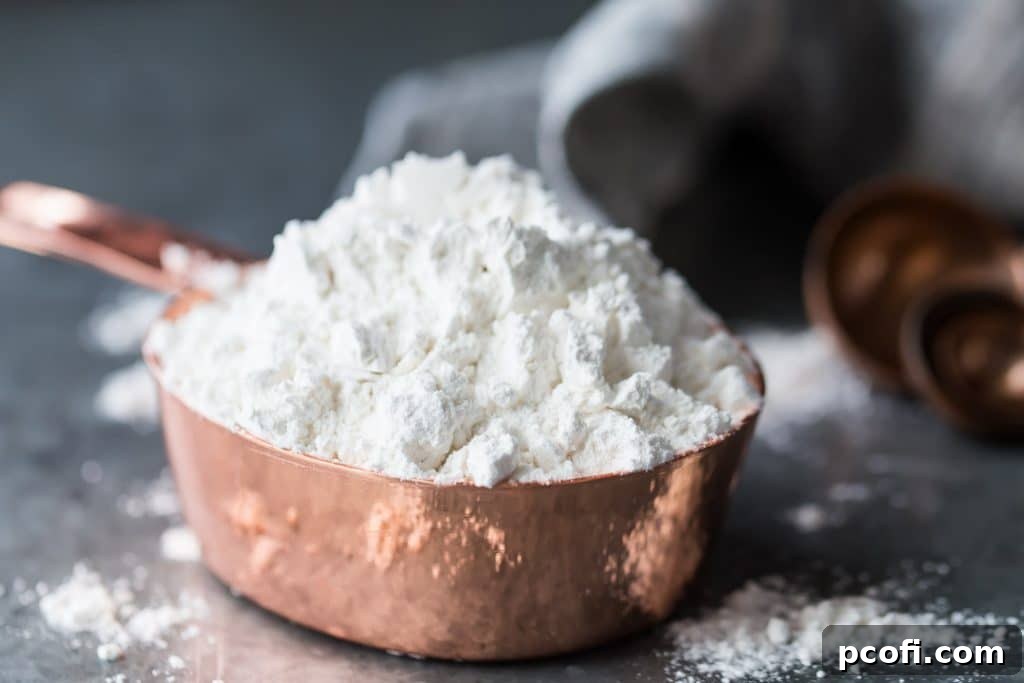 A close-up horizontal image of a copper measuring cup filled with cake flour, perfectly leveled, ready for precise baking measurements.