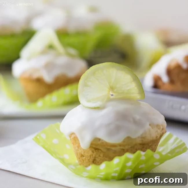 Beautifully baked Coconut Lime Glazed Muffins with a lime slice garnish on a rustic wooden board, ready to be enjoyed.