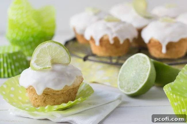 A plate of two Coconut Lime Glazed Muffins, garnished with fresh lime slices, ready to be served.