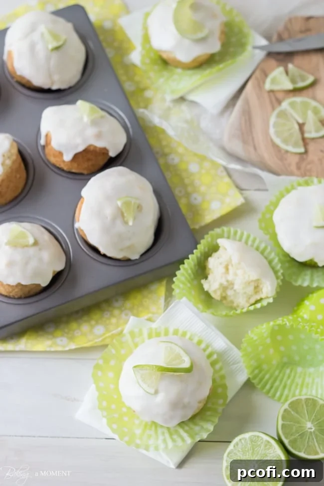 A close-up shot of a Coconut Lime Glazed Muffin, showing the textured glaze and a thin lime slice on top.