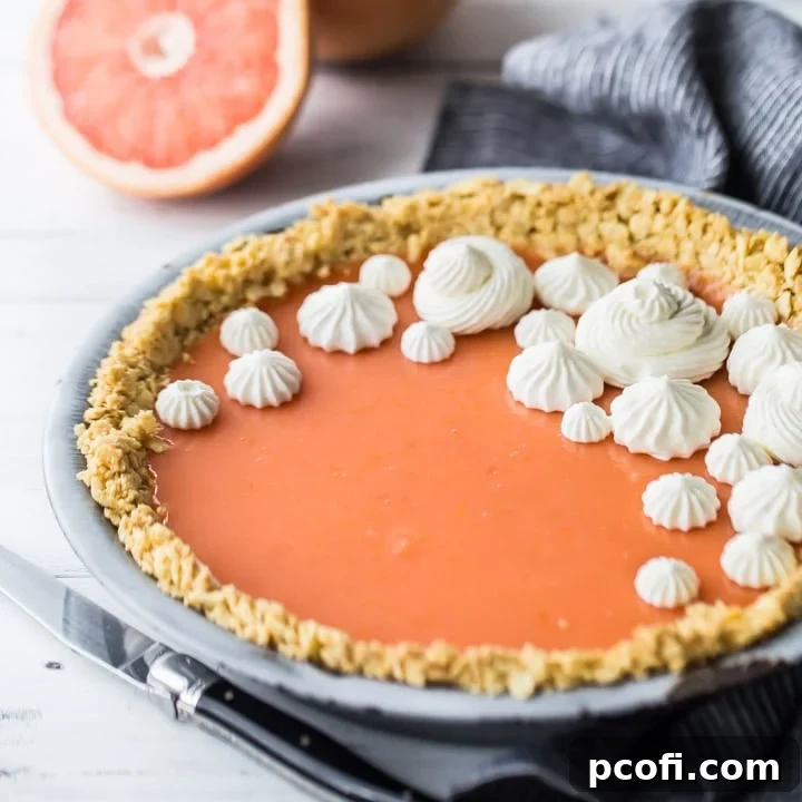 Square image of Paloma cocktail (grapefruit tequila) pie with Saltine cracker crust, on a white background with fresh grapefruit in the background.