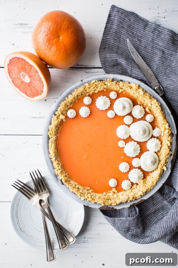 Vertical overhead image of Paloma cocktail (grapefruit tequila) pie on a white background with fresh grapefruit, plates, and forks.