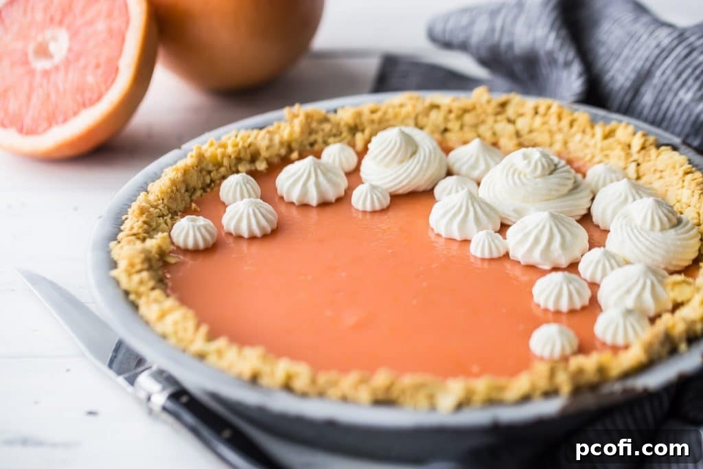 Horizontal image of Paloma cocktail (grapefruit tequila) pie on a white background with fresh grapefruit in the background.