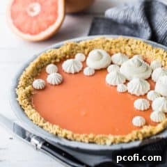Square image of Paloma cocktail (grapefruit tequila) pie with Saltine cracker crust, on a white background with fresh grapefruit in the background.