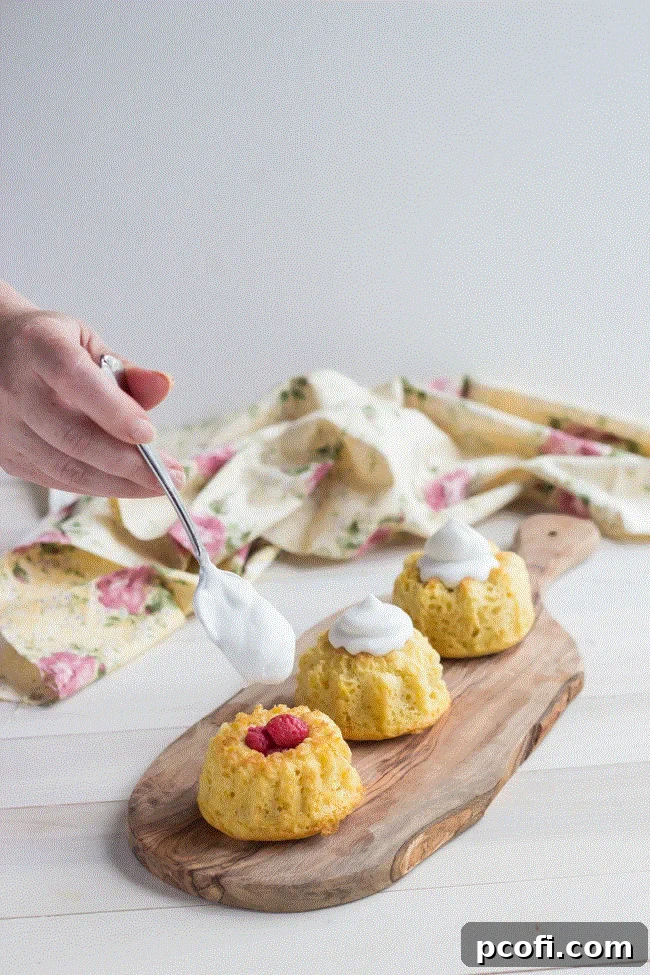 Close-up of a mini orange raspberry bundt cake with fresh raspberries and coconut cream, showcasing its intricate details.