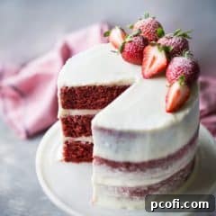 Moist triple-layer red velvet cake with cream cheese frosting and fresh strawberries.