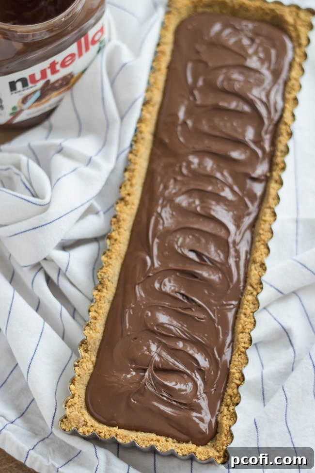 Nutella being spread over the graham cracker crust