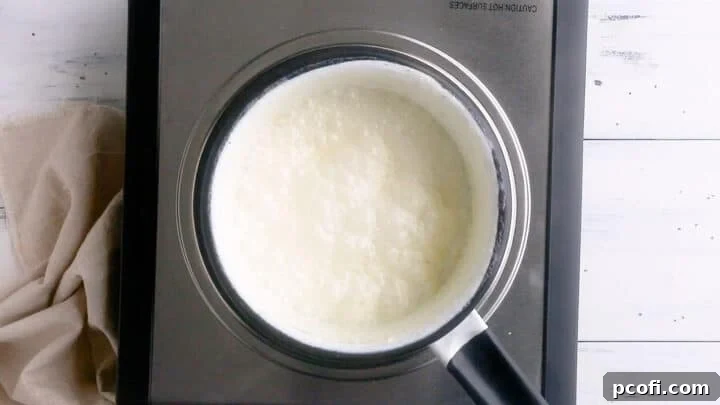 A small pot containing heavy cream simmering gently on the stove.