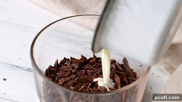 Hot heavy cream being poured over a bowl of finely chopped chocolate.