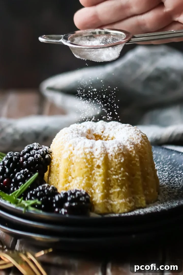 A simple olive oil cake being gracefully dusted with powdered sugar using a small sieve, enhancing its presentation.
