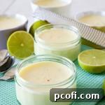 A vibrant Key Lime Posset served in a clear ramekin, garnished with lime zest and fresh berries, showcasing its creamy texture.