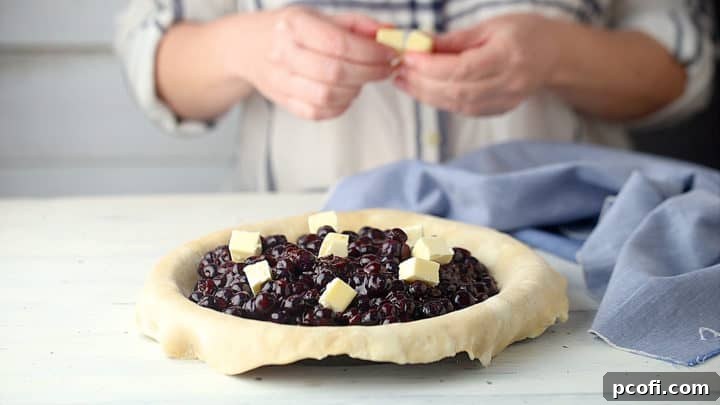Dotting blueberry pie with butter.