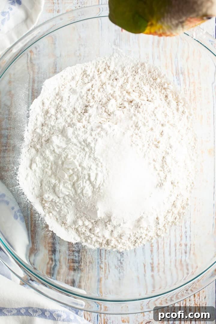A bowl filled with dry ingredients for making waffles, including flour, sugar, baking powder, and salt, ready to be whisked together.