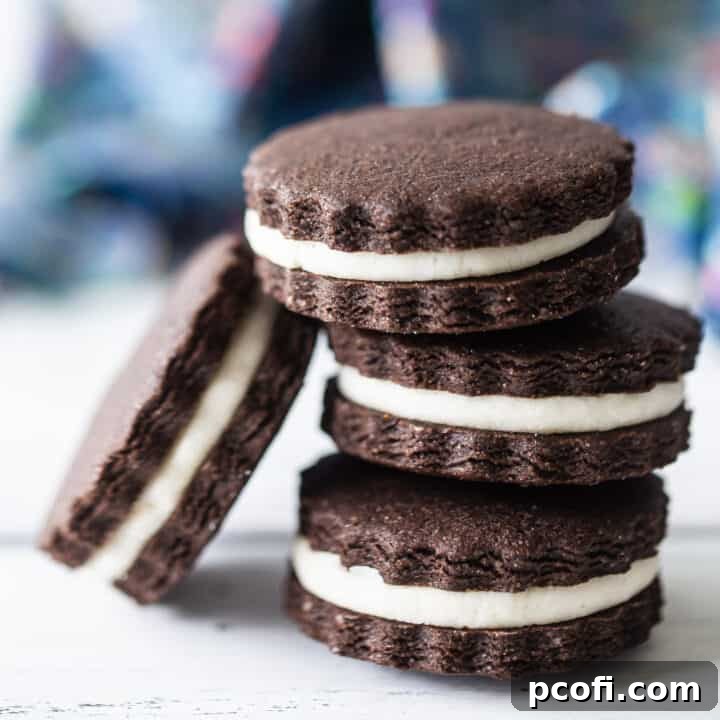 Homemade Oreos stacked on a white surface with a blue napkin in the background, showcasing their perfect layers.
