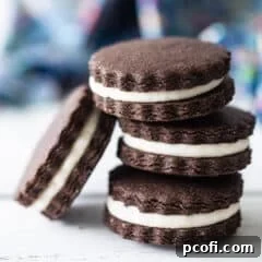 Homemade Oreos stacked on a white surface with a blue napkin in the background.