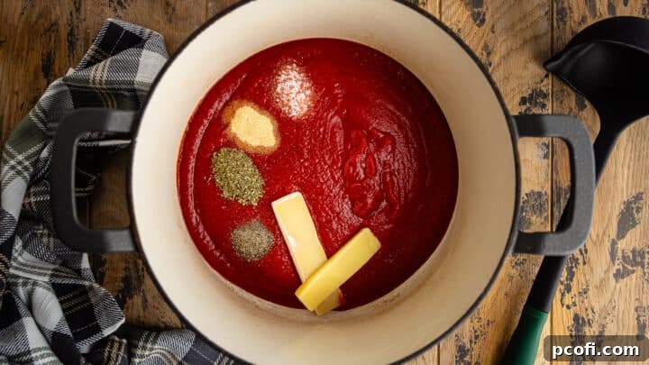 Crushed tomatoes and seasonings in a large, enameled cast iron Dutch oven.
