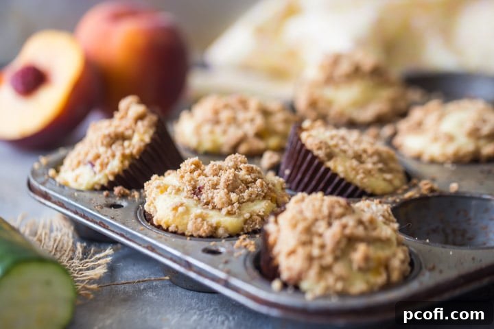 Close-up of freshly baked Crumb Topped Zucchini Peach Muffins cooling on a rack.