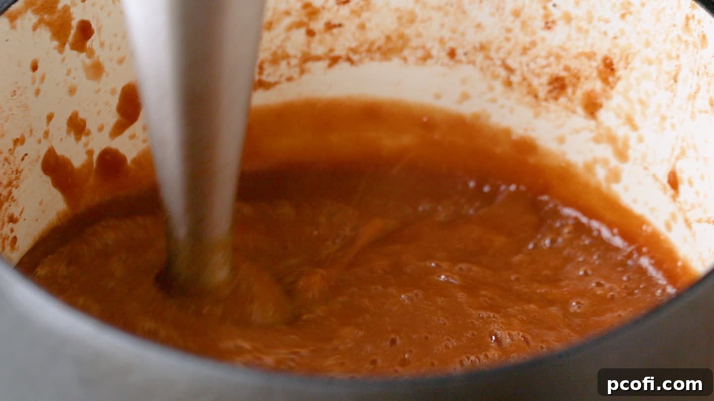 Pureeing homemade apple butter with a hand blender.