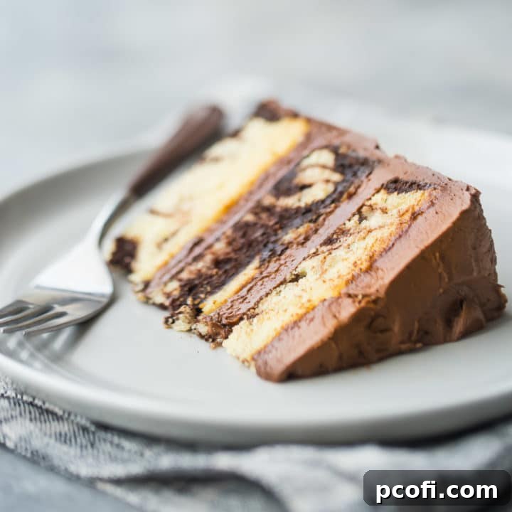 A perfectly sliced piece of moist marble cake with chocolate frosting, presented invitingly on its side.