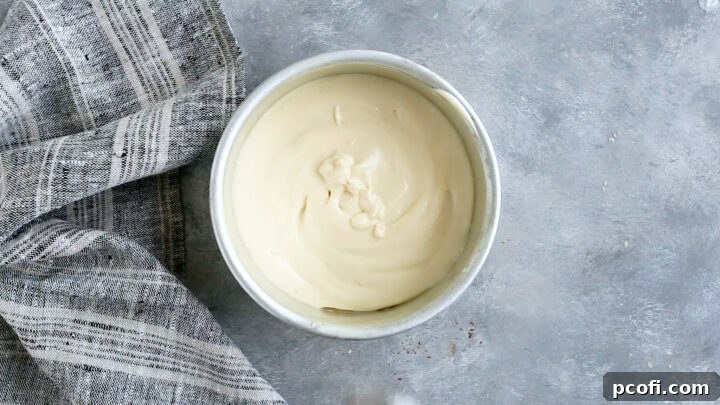 Half of the prepared vanilla cake batter already transferred into a greased and parchment-lined cake pan.