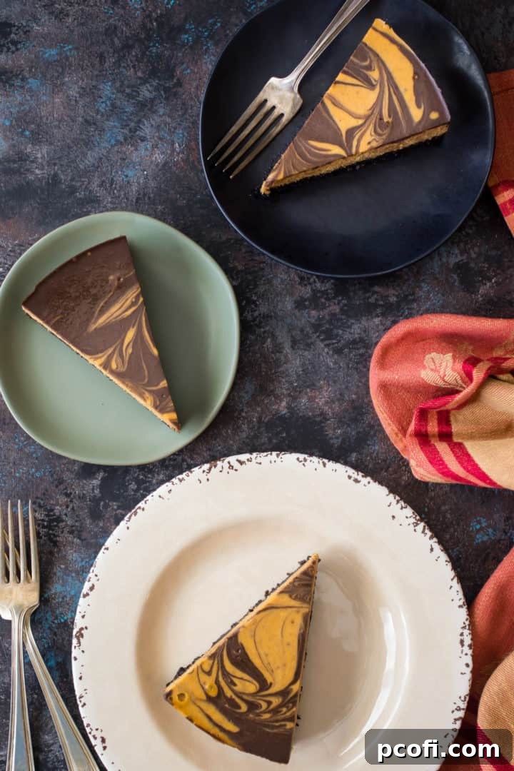 A slice of Pumpkin Chocolate Swirl Cheesecake on a plate, showing the distinct layers and elegant marble effect. The smooth filling contrasts with the crunchy chocolate crust.