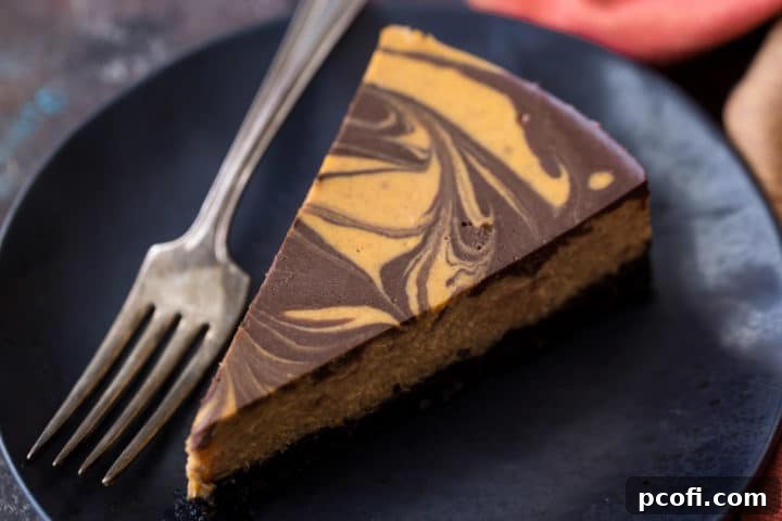 Overhead shot of a full Pumpkin Chocolate Swirl Cheesecake, with a few slices cut, revealing the stunning marble pattern. Perfect for autumn entertaining.