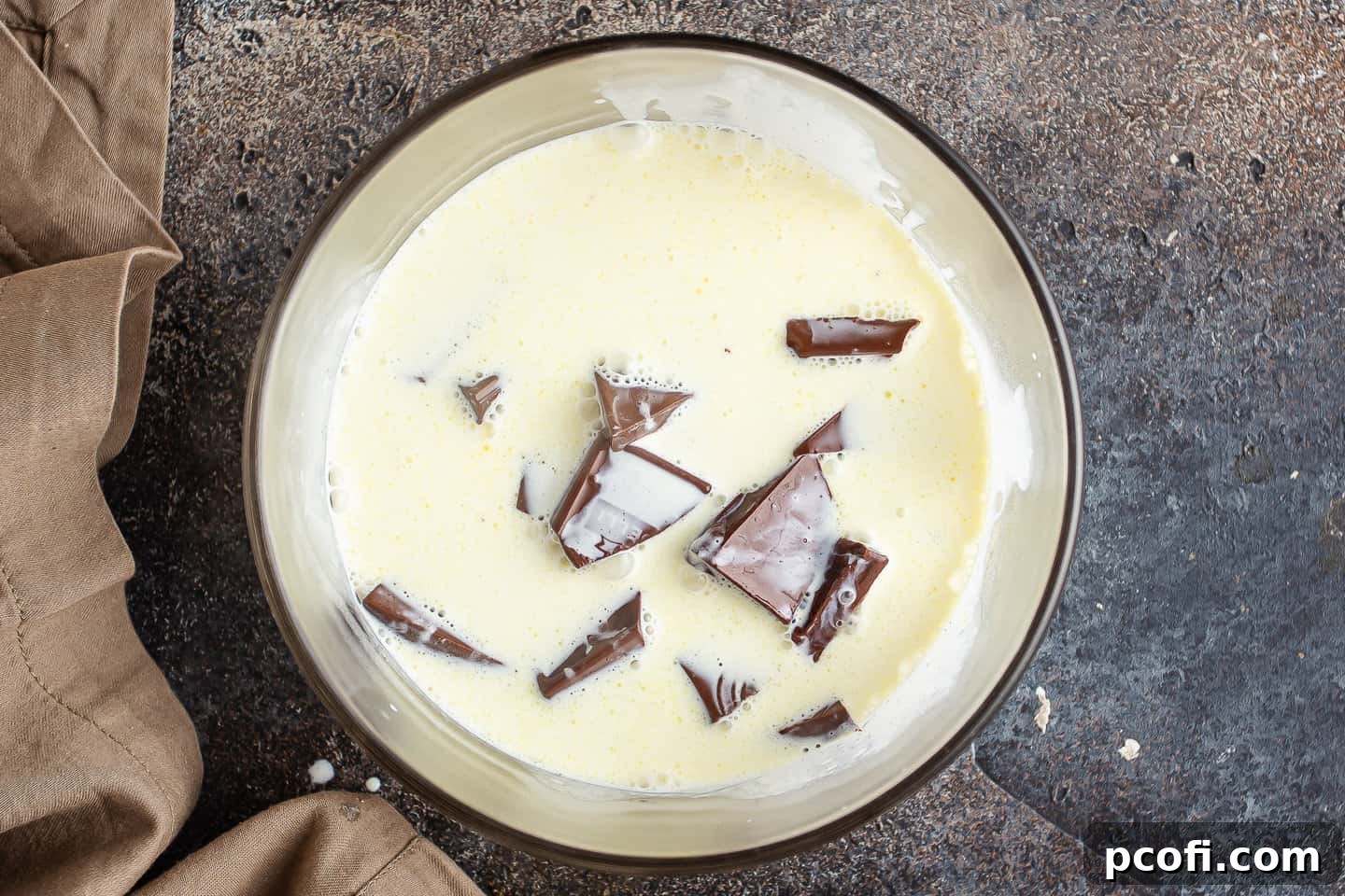 Hot cream poured over chopped chocolate and corn syrup in a small bowl, softening the chocolate for the glaze.