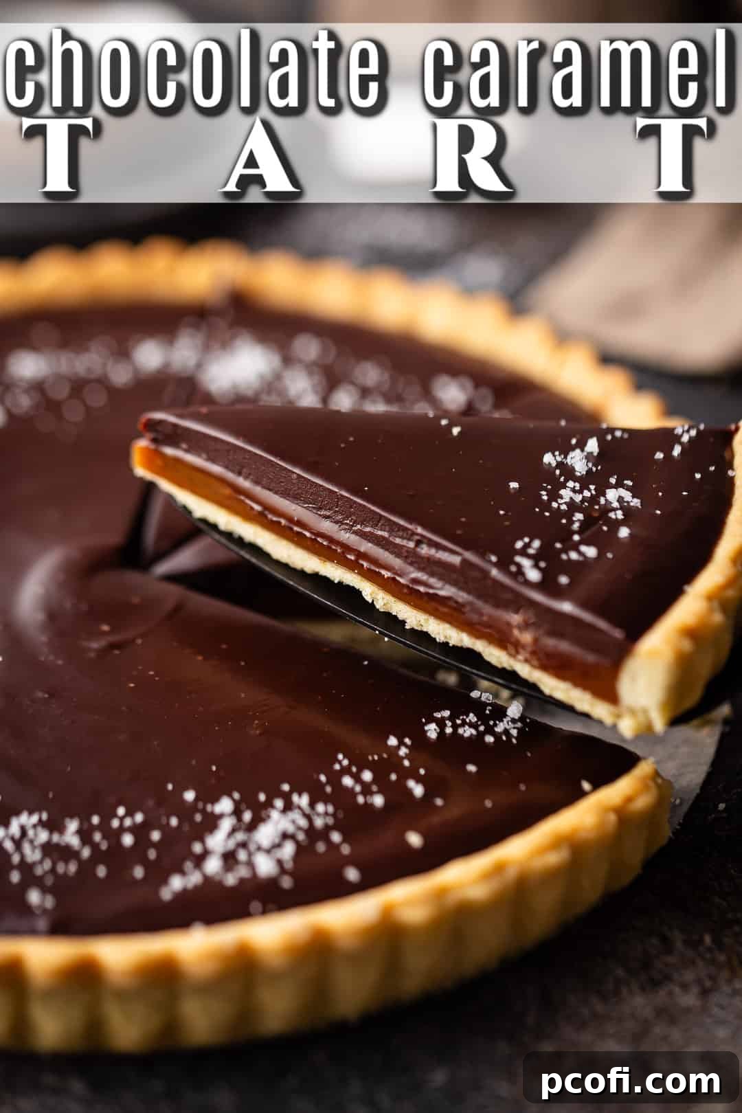 A beautifully cut slice of salted caramel chocolate tart is being served, showcasing the distinct layers of crust, caramel, and chocolate.