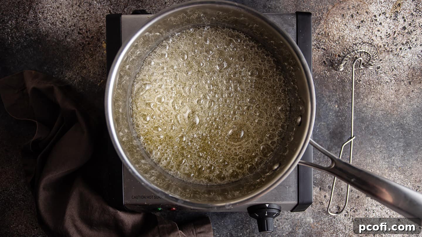 The sugar syrup actively boiling in a medium stainless steel pot, indicating the start of the caramelization process.