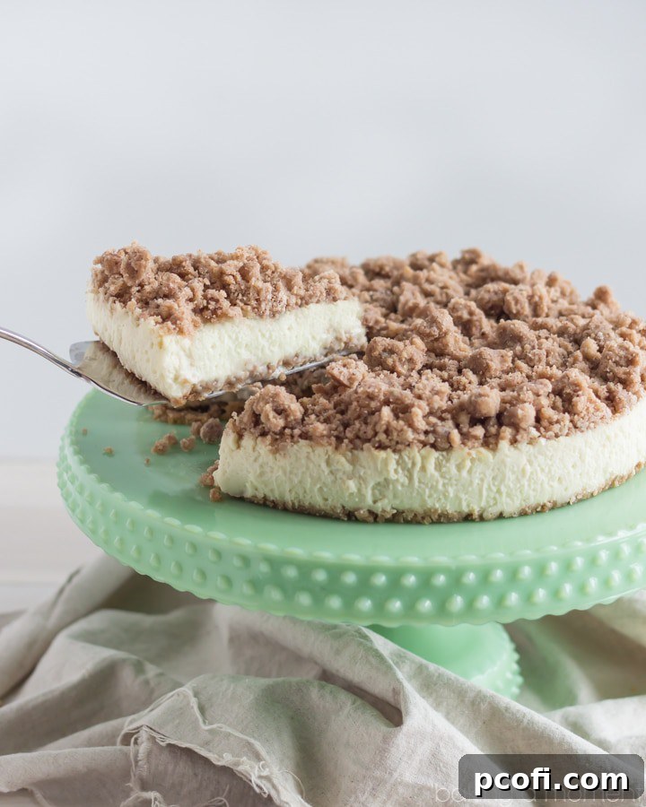 A whole New York Crumb Cheesecake cooling, showcasing its perfectly browned crumb topping and smooth, golden edges.
