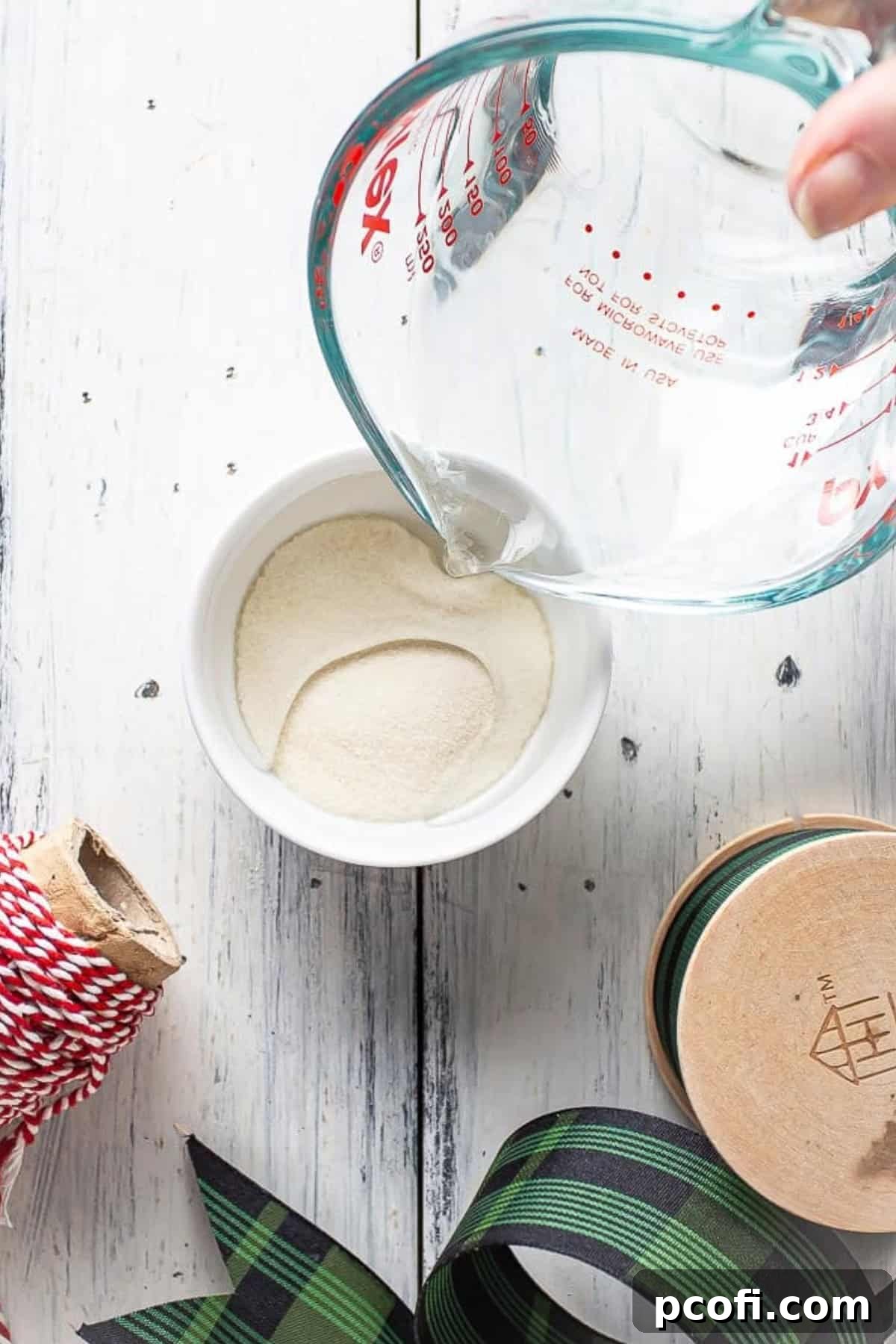 Pouring water into gelatin powder to bloom it in a small bowl.