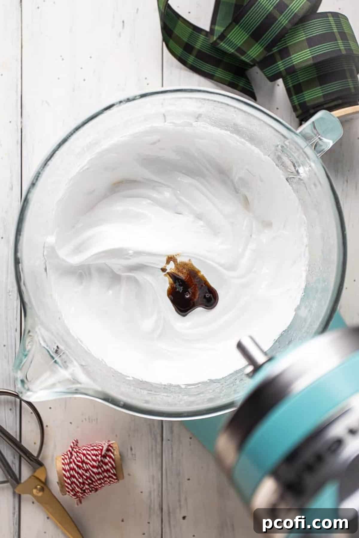 Whipping egg whites into stiff peaks with vanilla extract added, in a stand mixer.