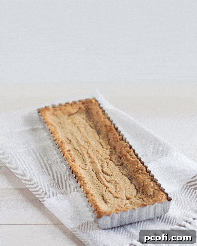 Close-up of a Snickers Blondie Tart with a luscious layer of salted caramel drizzled over crunchy peanuts.