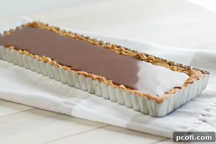 A close-up shot of the gooey salted caramel and rich chocolate ganache layers in the Snickers Blondie Tart, showcasing its irresistible texture.