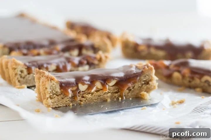 A final close-up of the completed Snickers Blondie Tart, highlighting the vibrant colors and layers of peanut butter, caramel, and chocolate.