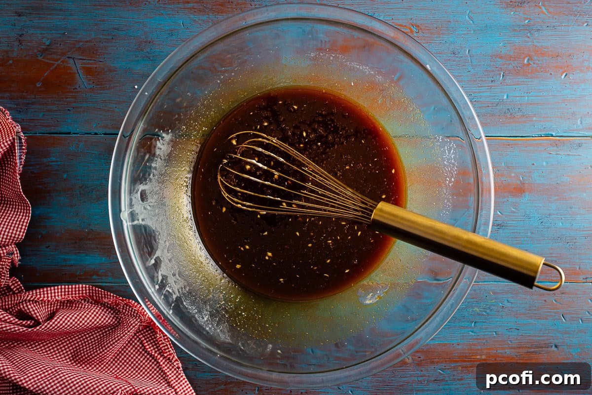 Brown sugar, dark molasses, and a single egg are added to the butter and hot water mixture in a large mixing bowl, ready to be whisked for the gingerbread cake batter.