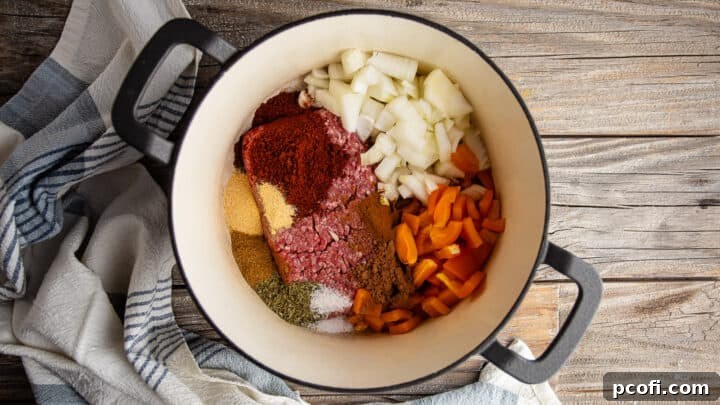 Ground meat, spices, and vegetables cooking in a large pot for the best chili con carne recipe.
