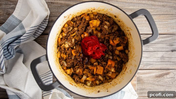 Adding tomato paste to the easy chili recipe, browning it at the bottom of the pot.