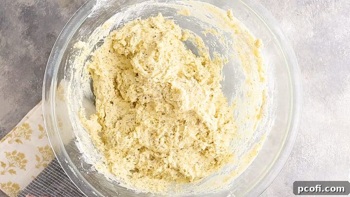 Stiff lemon poppy seed muffin batter in a mixing bowl, perfectly combined.