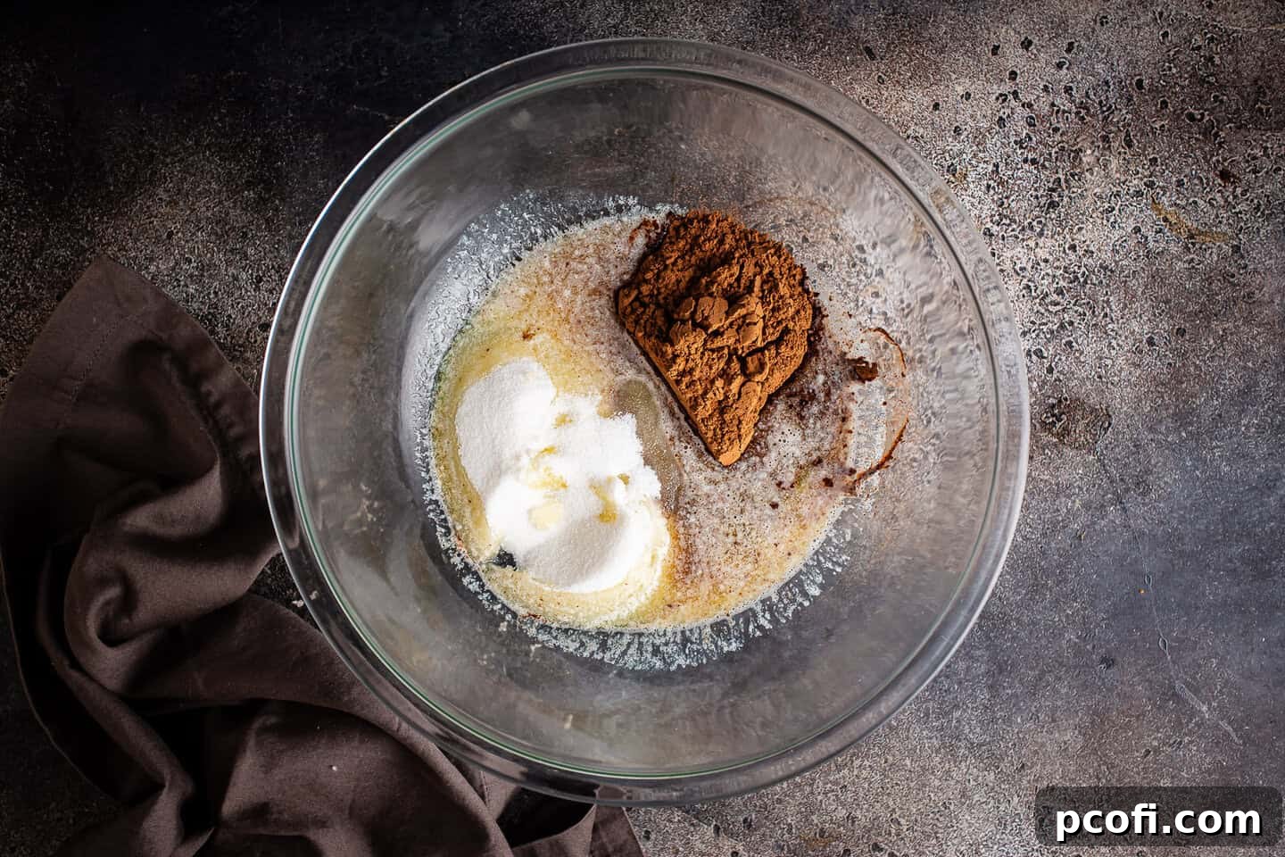 Heating sugar, cocoa, and butter together in a microwave-safe bowl until the butter is melted and mixture is warm.