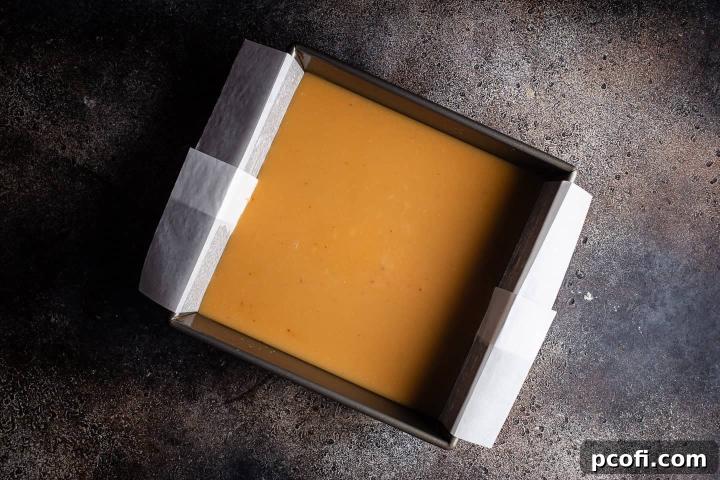 Salted caramel poured into a square baking pan and cooling, ready for the brownie layer.